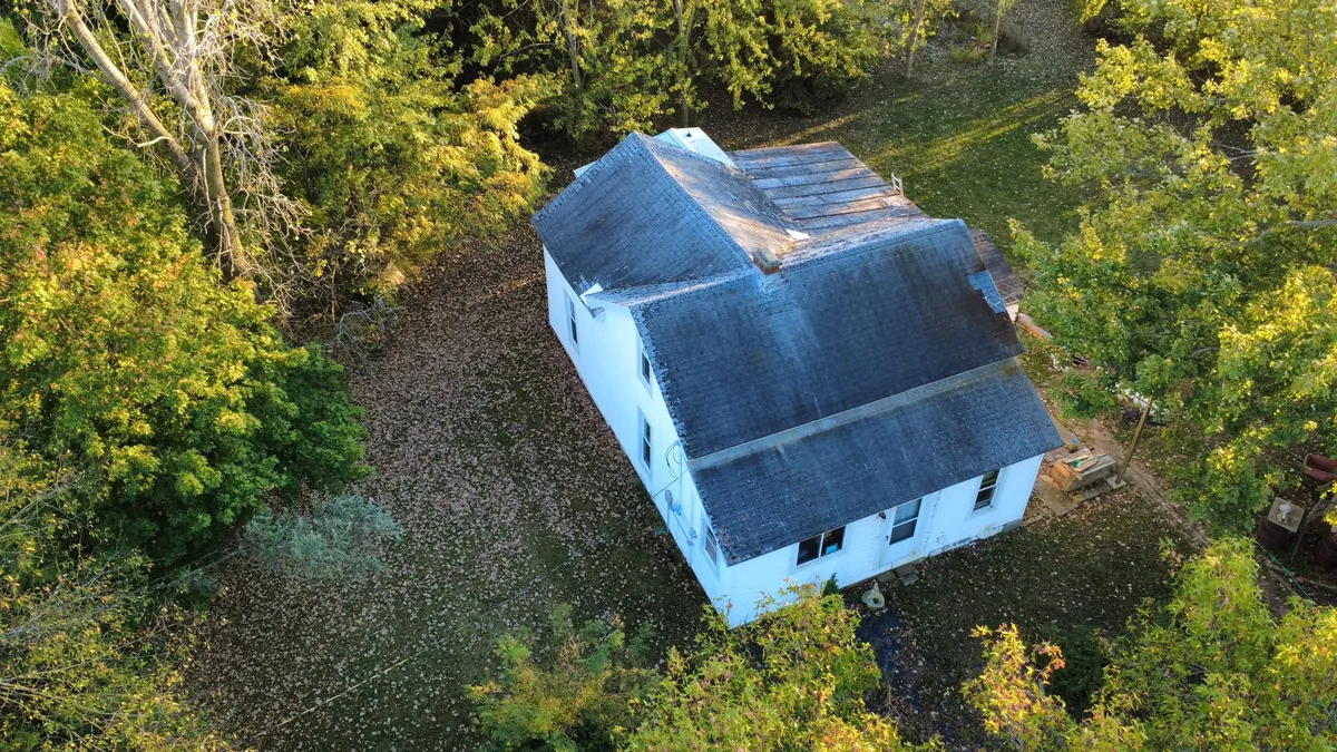 Farmhouse with a new roof surrounded by trees in rural Henry County, Ohio
