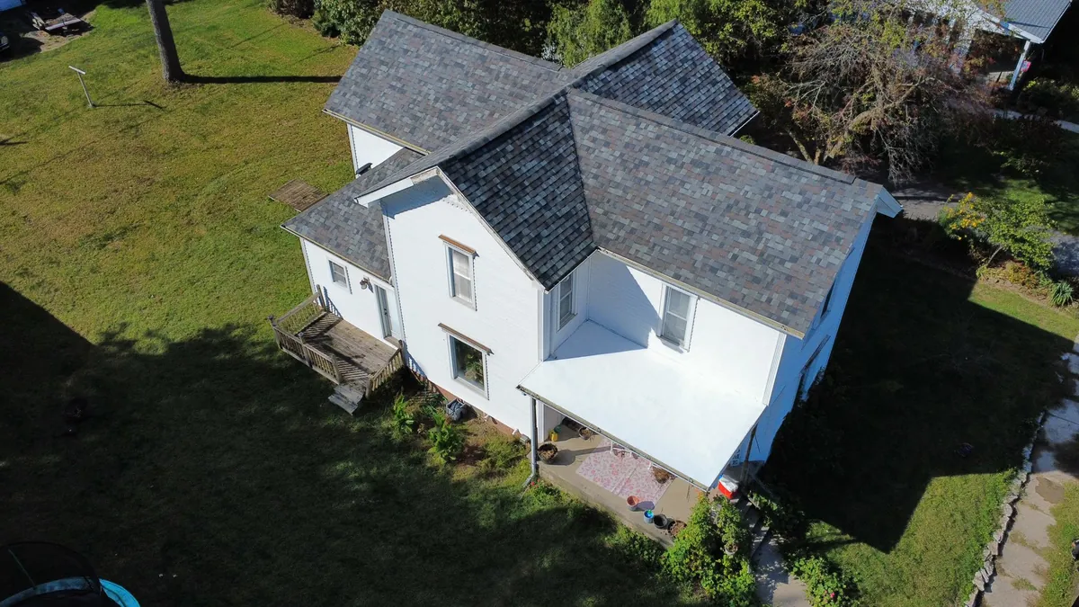 Aerial view of a white farmhouse with new roofing in rural NW Ohio