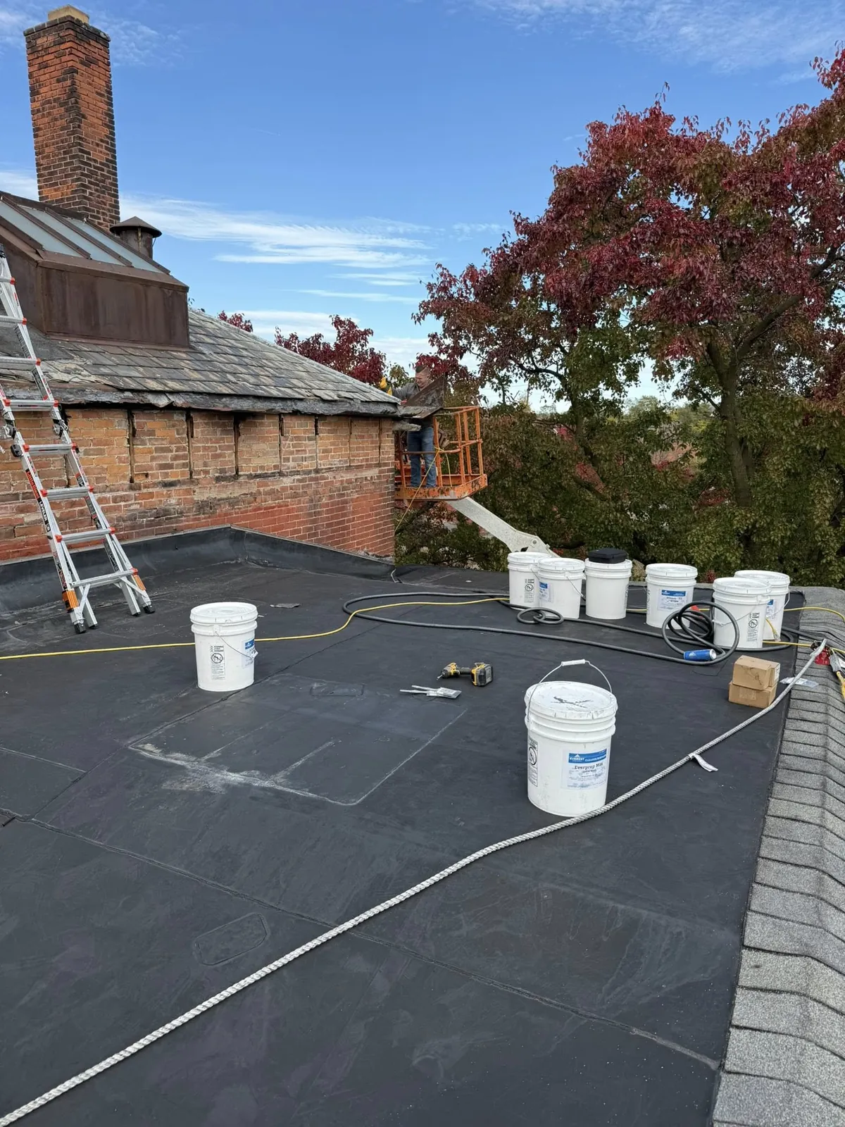 Commercial roof craftwork with buckets and materials on flat roof