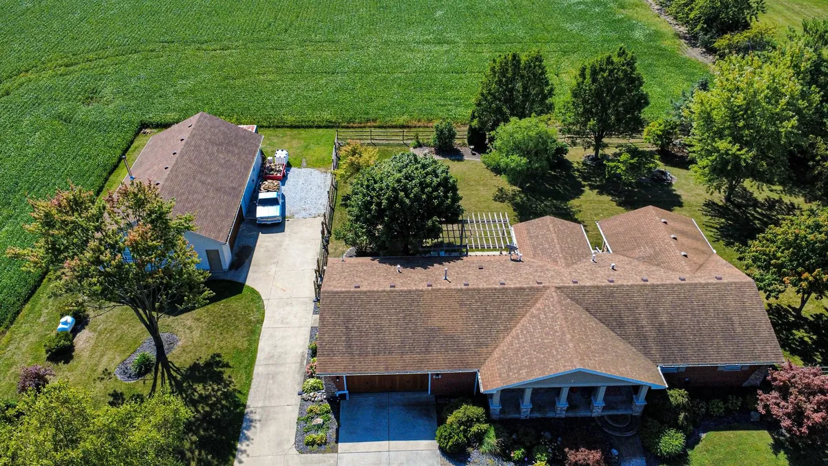 Aerial view of a ranch home with new roof surrounded by agricultural fields in NW Ohio