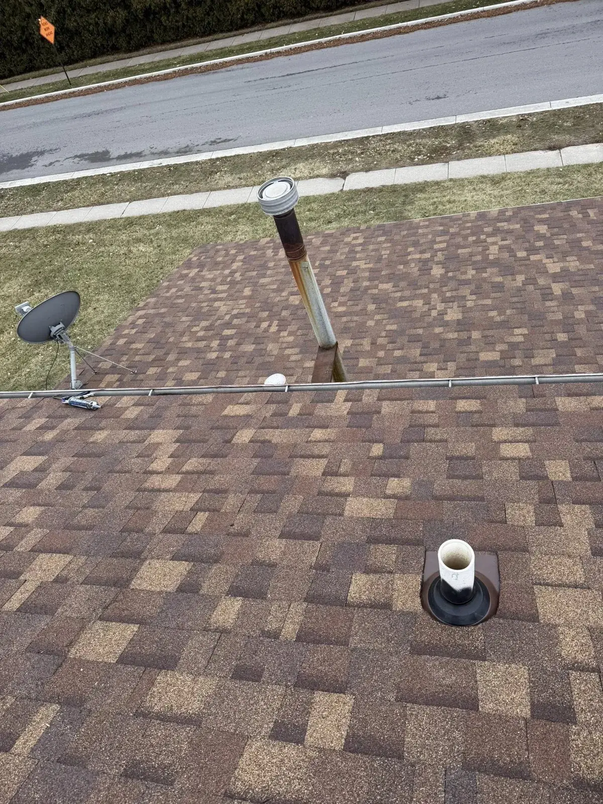 Close-up of a vent pipe boot on a shingle roof showing typical wear
