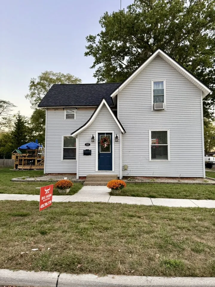 Restored white Victorian home in an older Archbold, Ohio neighborhood with a Big Horn Roofing yard sign